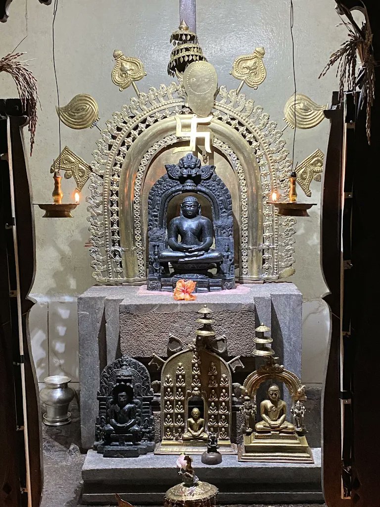 Bronze Anantnath idol surrounded by brass lamps and ritual offerings